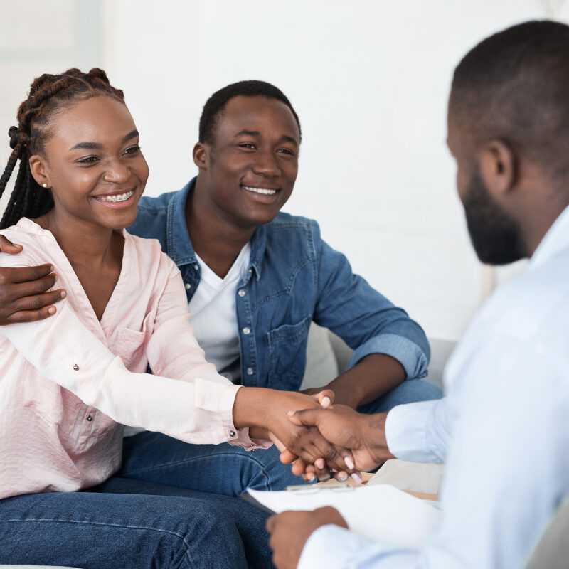 Marriage Counselling Concept. Grateful Black Couple Shaking Hands With Therapist After Session, Selective Focus